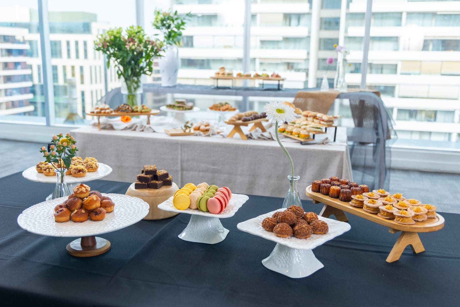 Mesa de banquetería montada con estaciones de dulces y bocados